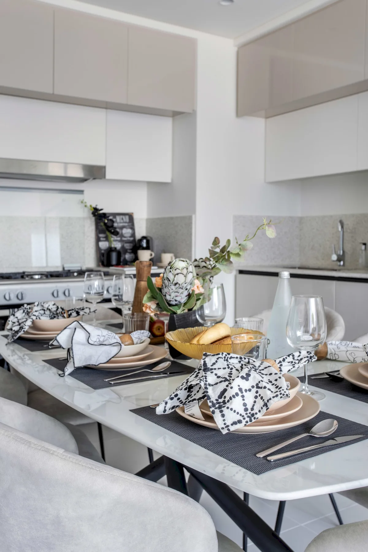 Una mesa de comedor puesta con platos y cubiertos en una cocina luminosa.