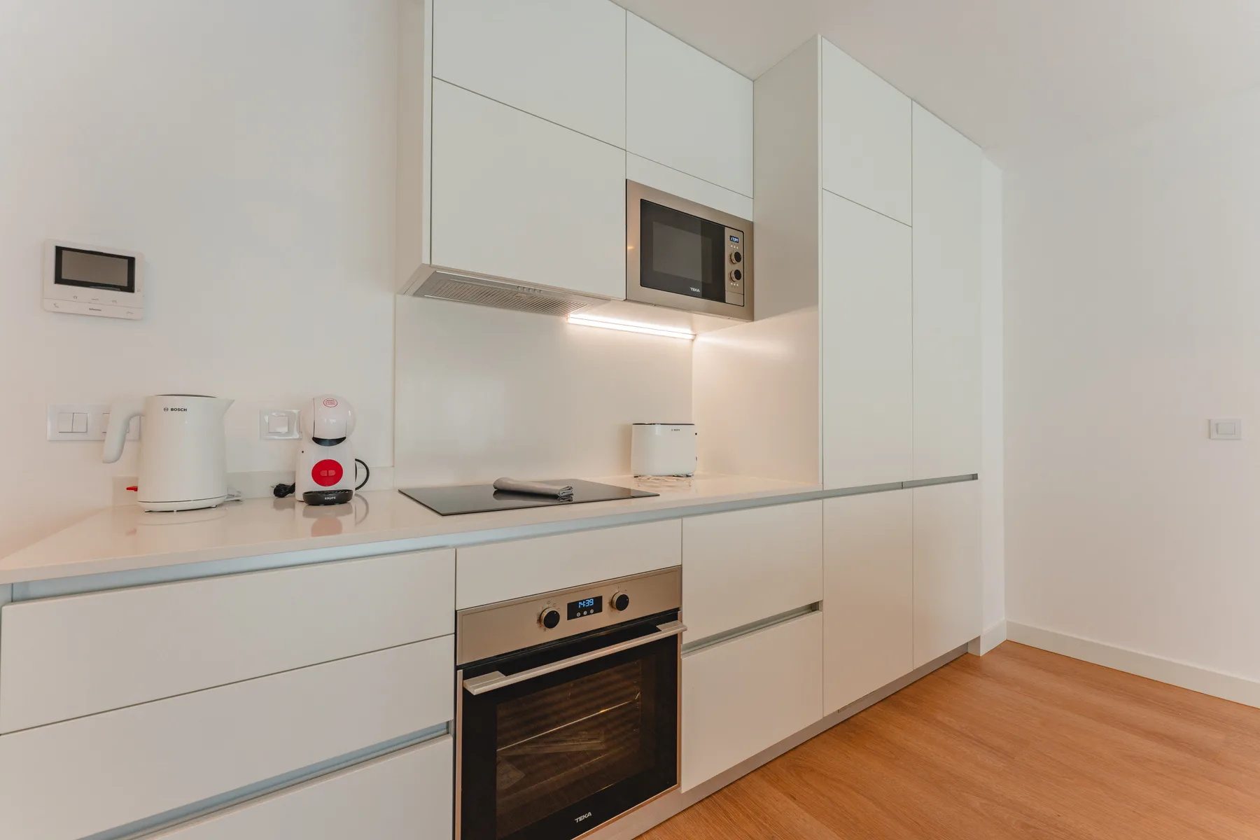 Una cocina moderna con gabinetes blancos, un microondas y un horno.