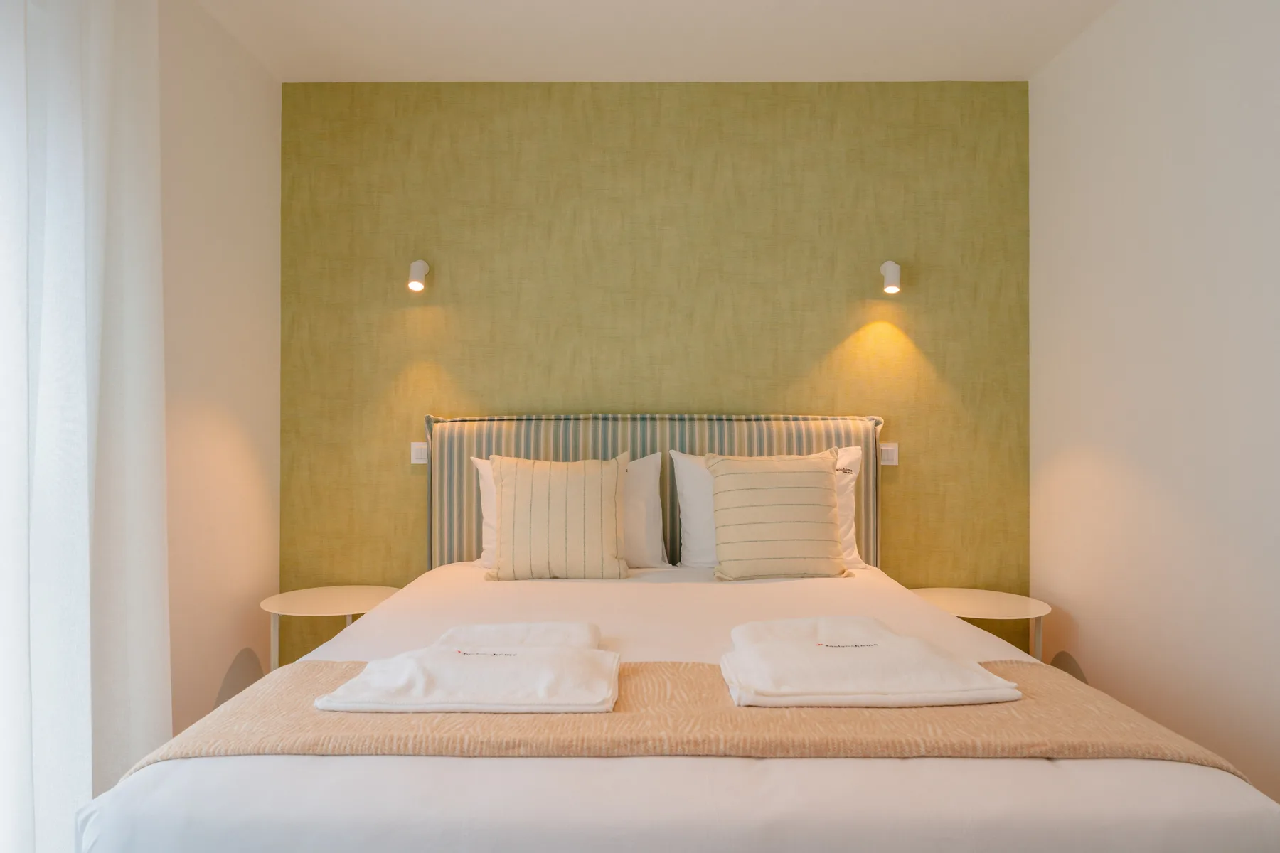 Un dormitorio con una cama bien tendida y mesas de noche.