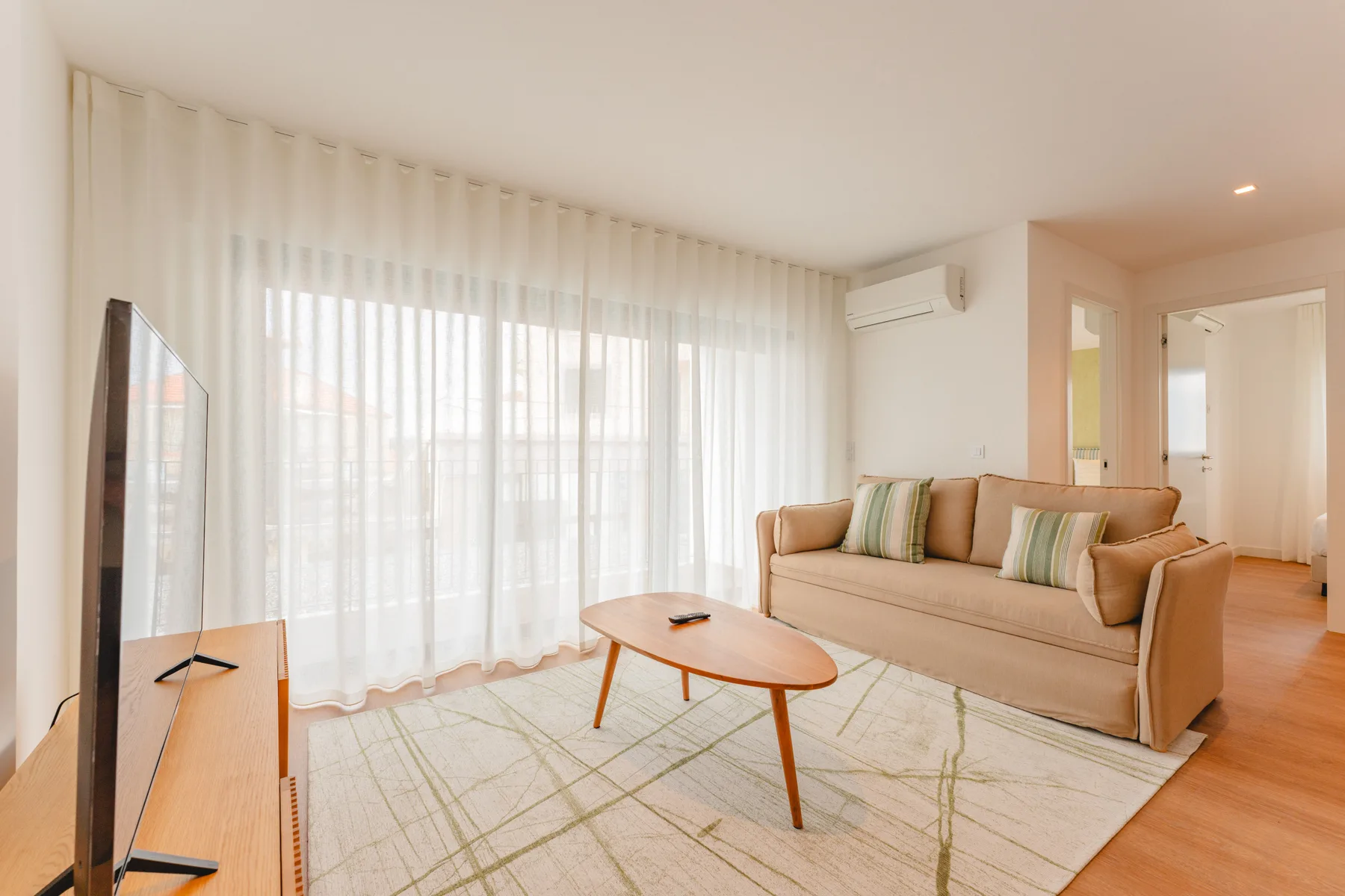 Una sala luminosa con asientos, una mesa de centro y grandes ventanas con cortinas.