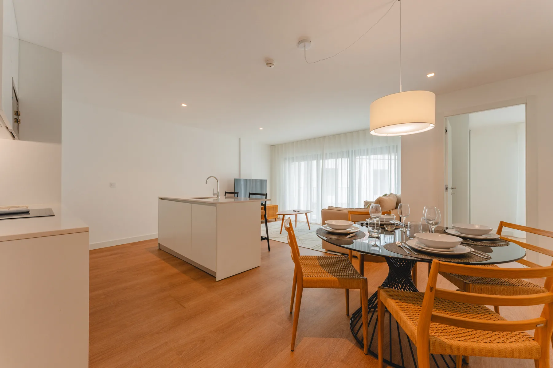 Una cocina abierta y zona de comedor con la mesa puesta junto a las ventanas.