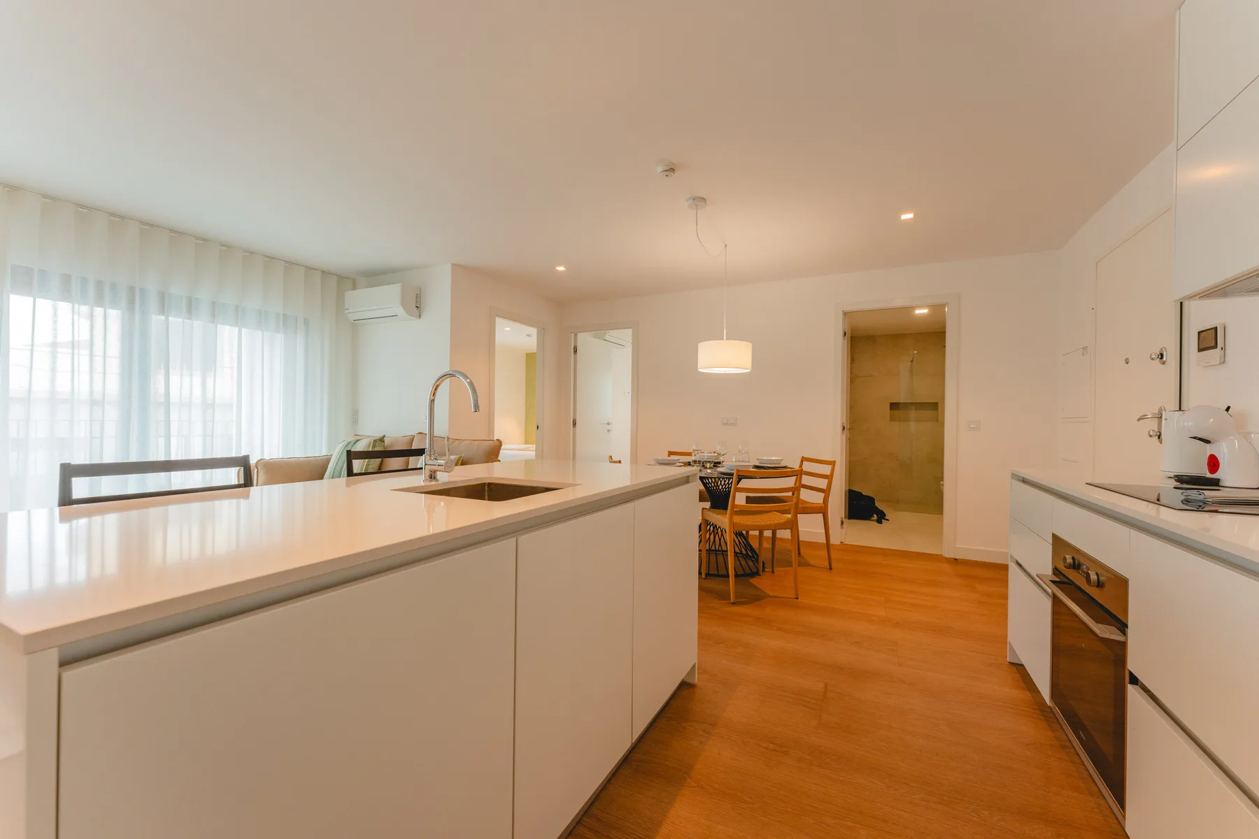 Una cocina luminosa con comedor, una encimera larga y suelo de madera.