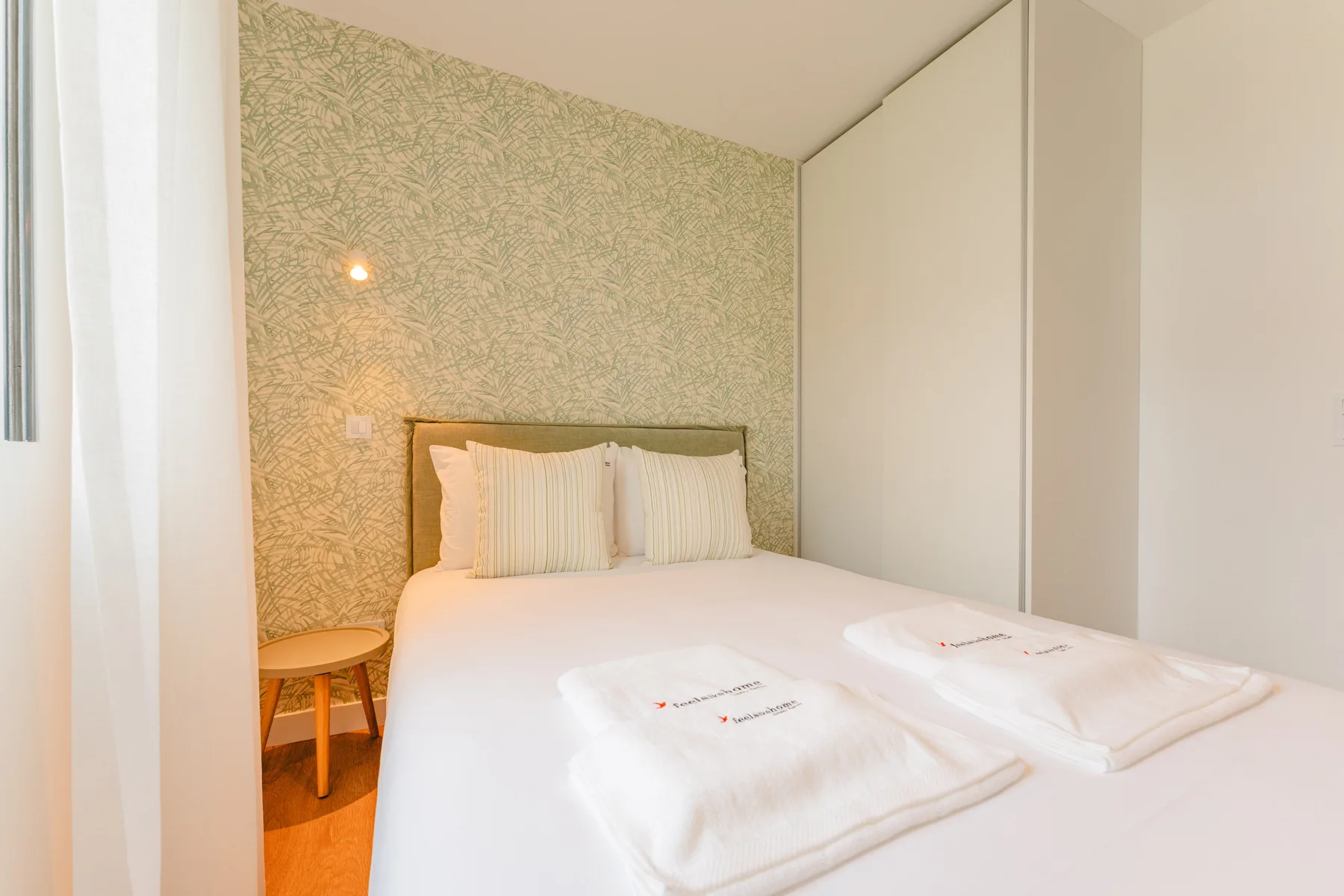 Un dormitorio con cama doble, mesita de noche y pared decorativa estampada.