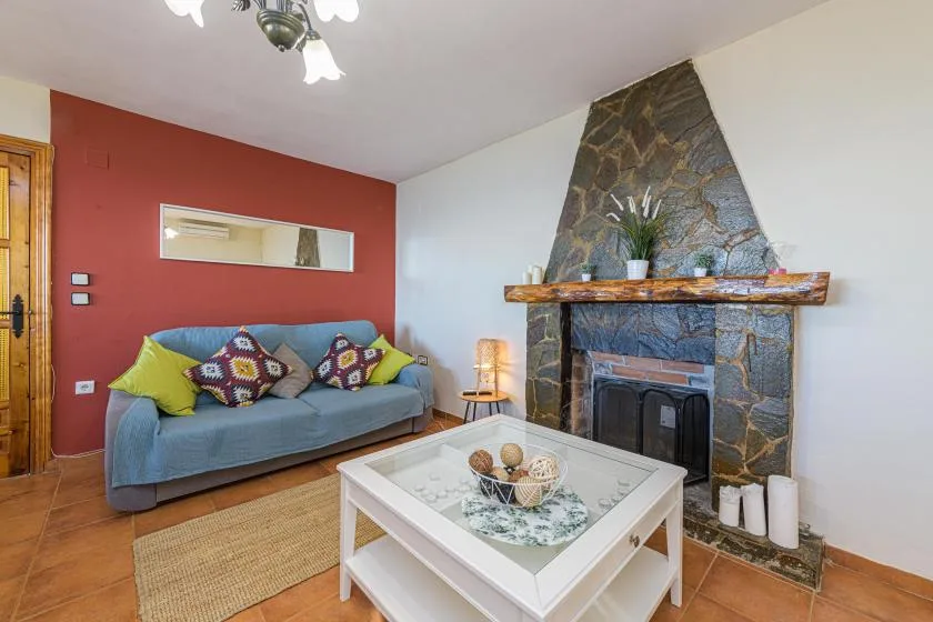 A living room with a sofa and a stone fireplace.