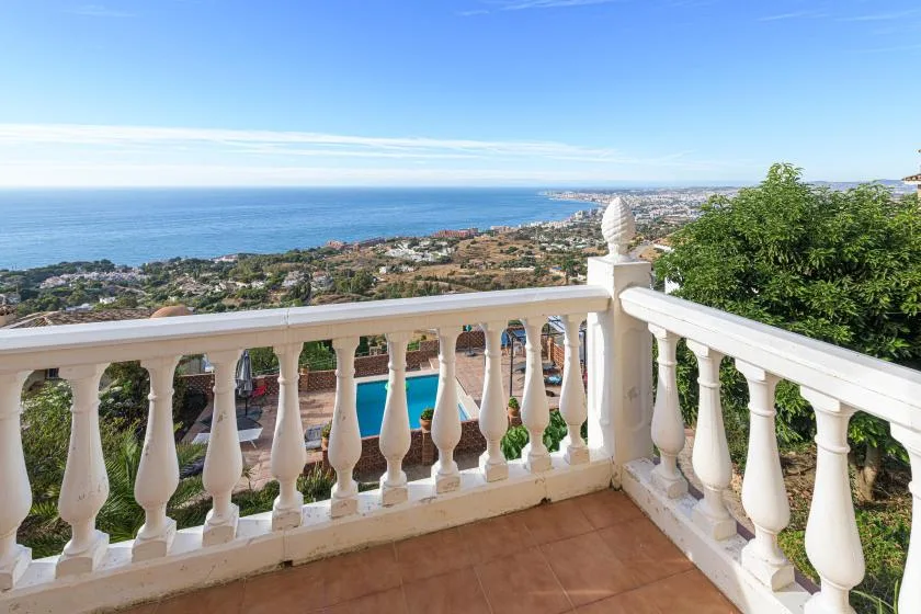 A tiled balcony overlooks the coastline and blue sea.