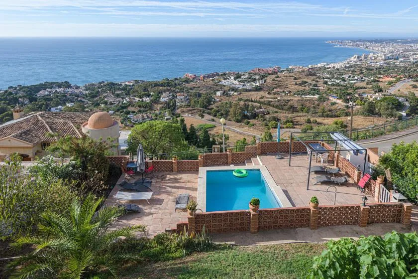 A terrace overlooks a swimming pool and the coastline.