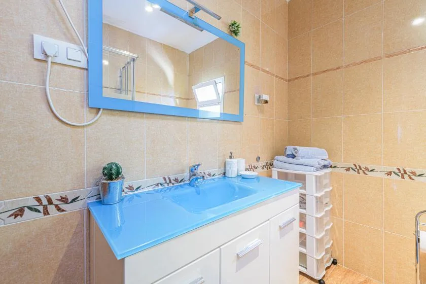 A tiled bathroom with a blue vanity sink and a large mirror.
