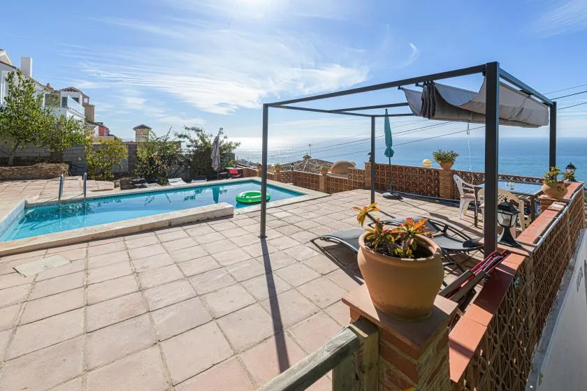 A tiled outdoor terrace with a swimming pool and ocean views.