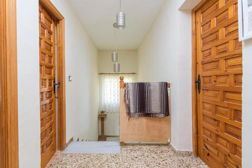 A bright hallway with wooden doors and a towel hanging over a half-height partition.