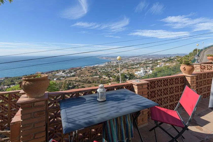 A terrace dining area overlooks a coastal town and the sea.