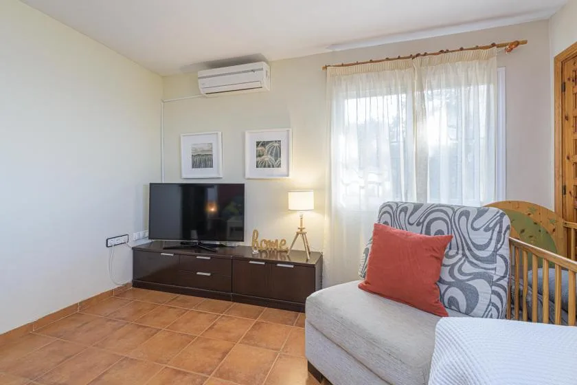 A living room with a television, seating, and a curtained window.