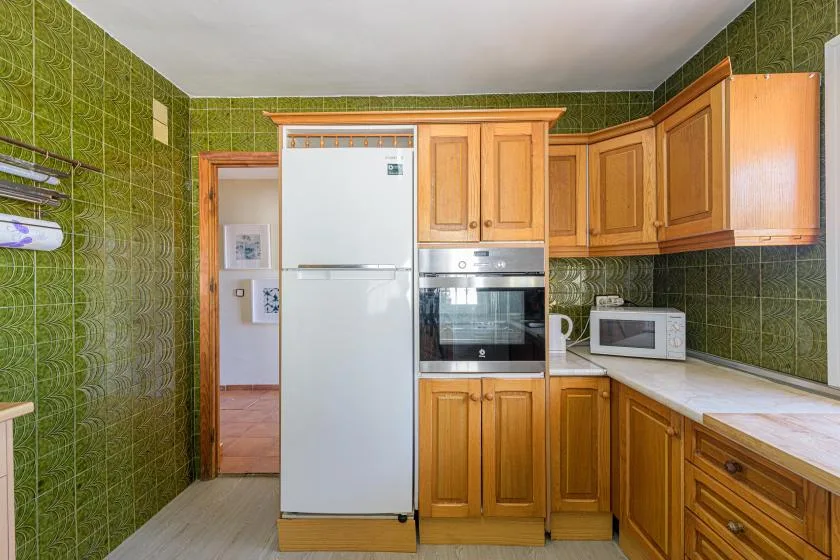 A kitchen with wooden cabinets, a refrigerator, and built-in appliances.