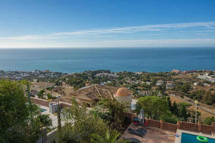 A coastal neighborhood overlooks the sea, with a swimming pool in the foreground.