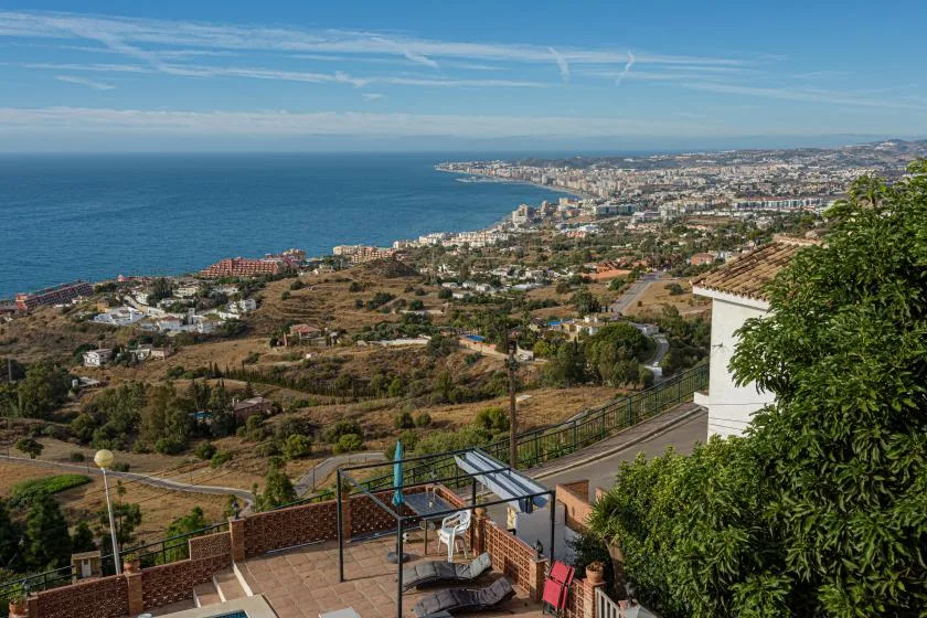 A coastal landscape overlooks the sea, with a town and hills along the shoreline.