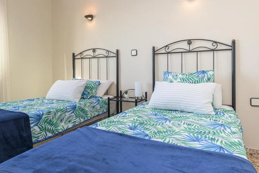 A bedroom with two beds dressed in blue and green leaf-patterned bedding.