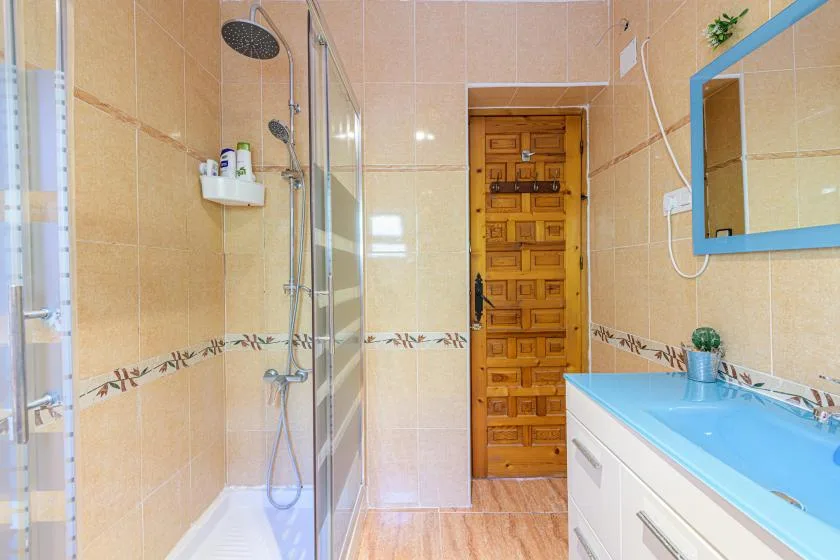 A tiled bathroom with a shower and a blue vanity.