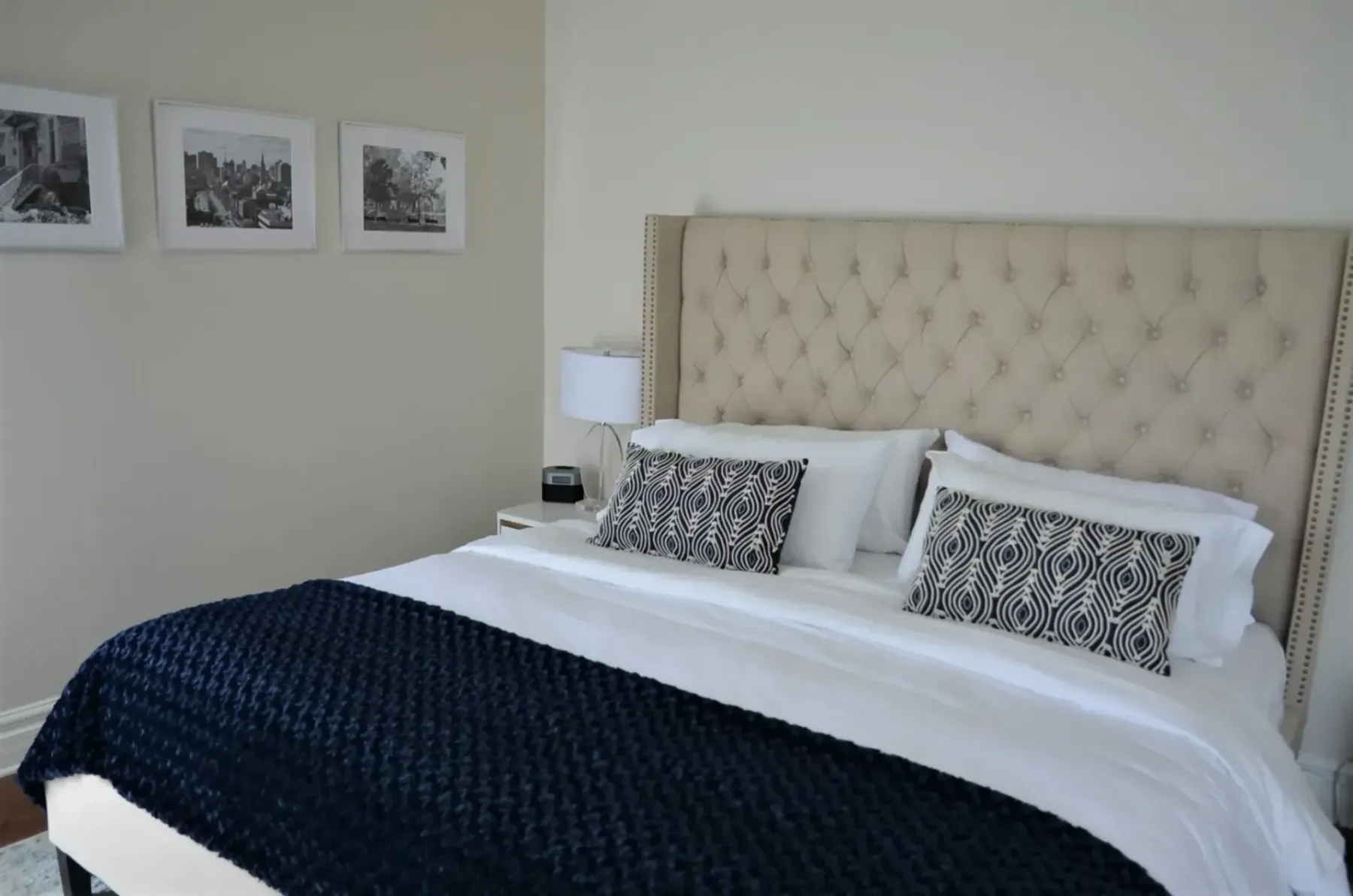 A hotel room bed with a blue cover and white sheets.