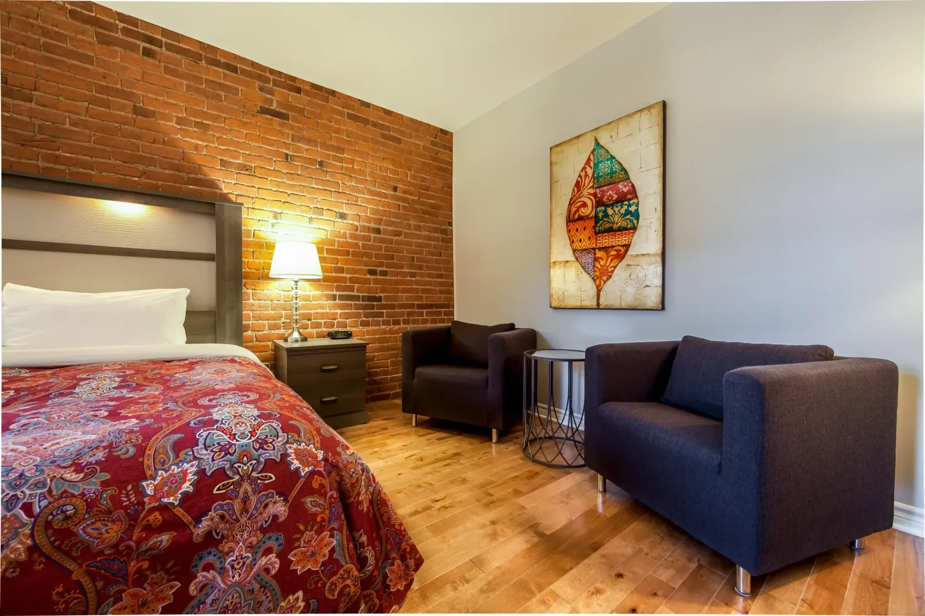 A hotel room with a bed and two chairs.