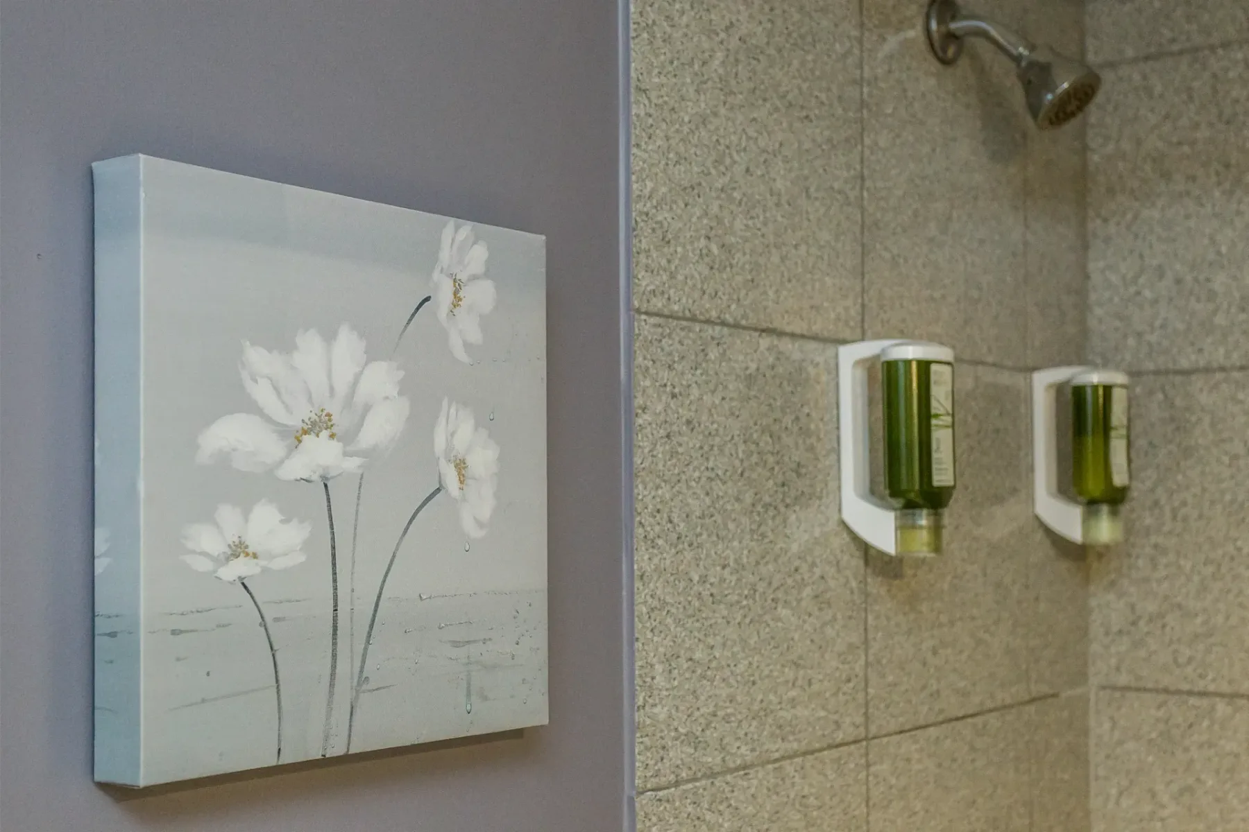 A bathroom area with a flower picture beside a shower.