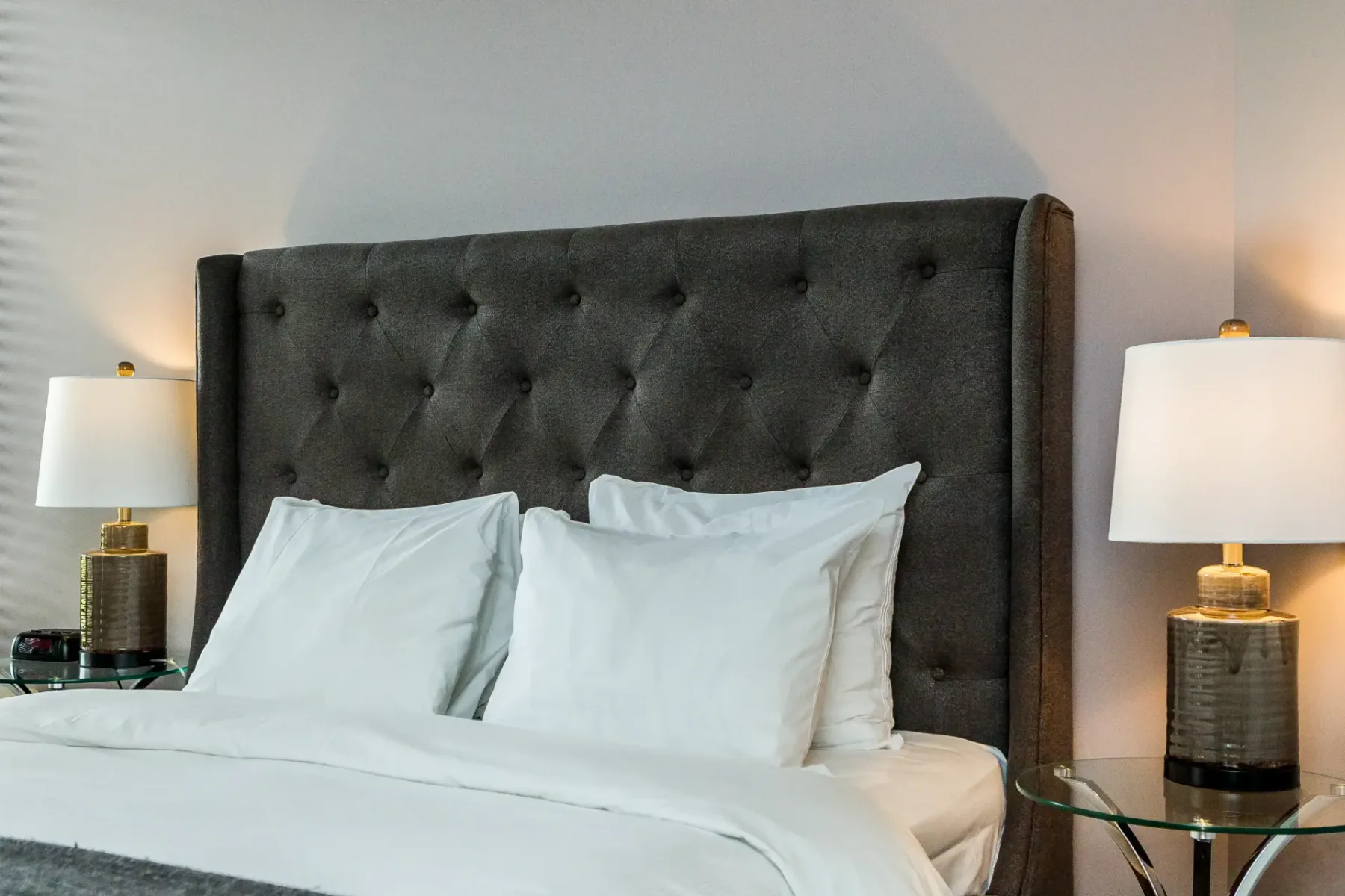 A hotel room with a bed and two lamps.