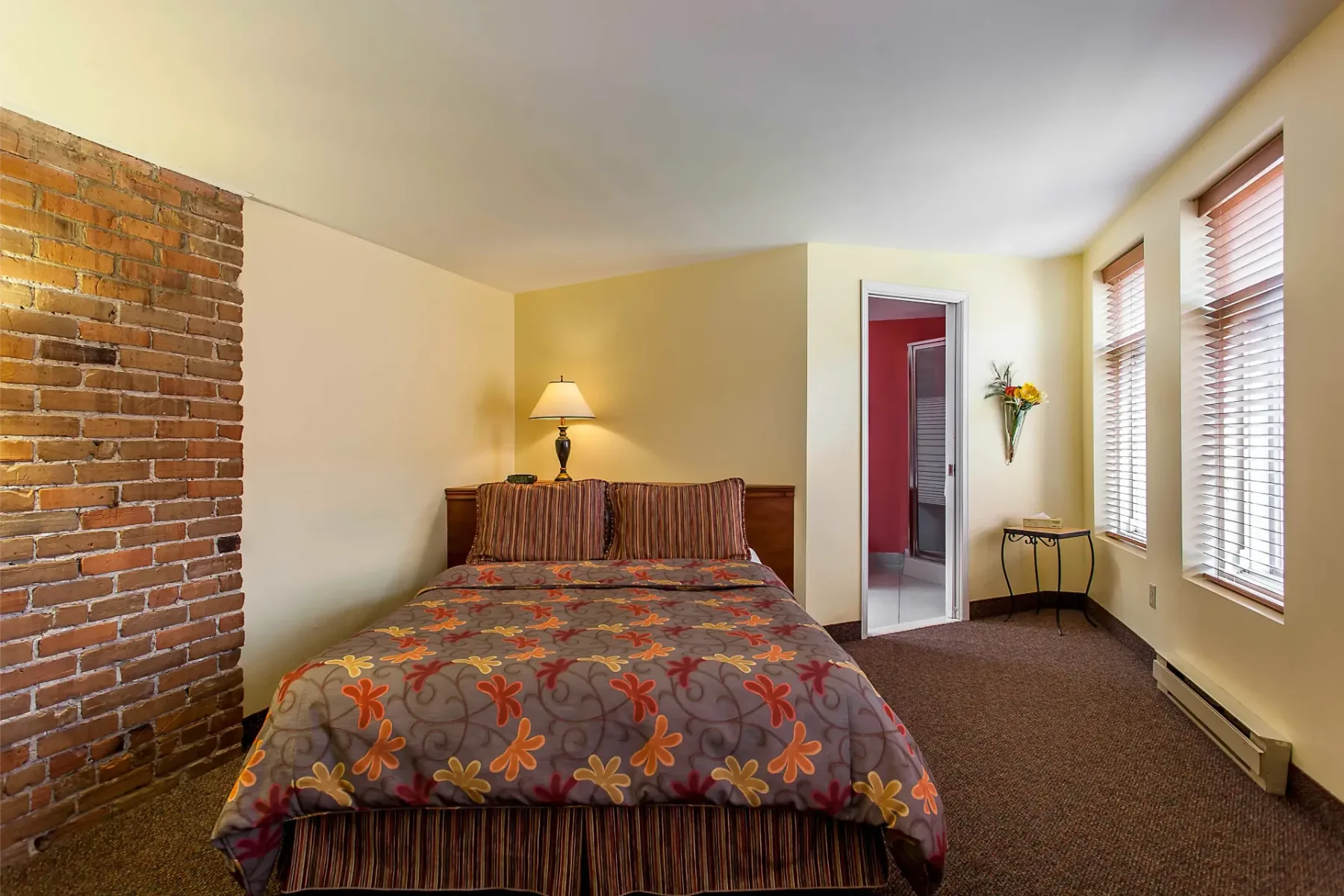 A hotel room with a bed and exposed brick wall.