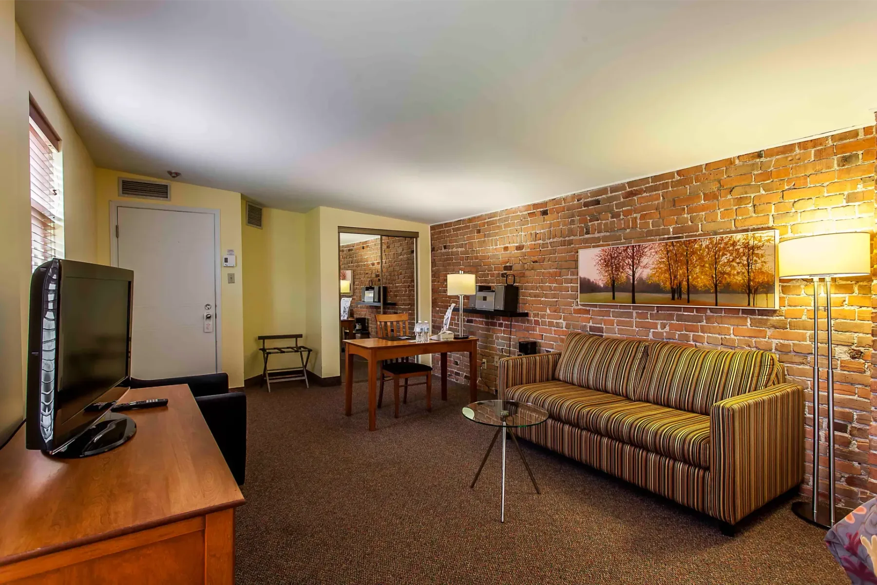 A hotel room with a sofa, table and television.
