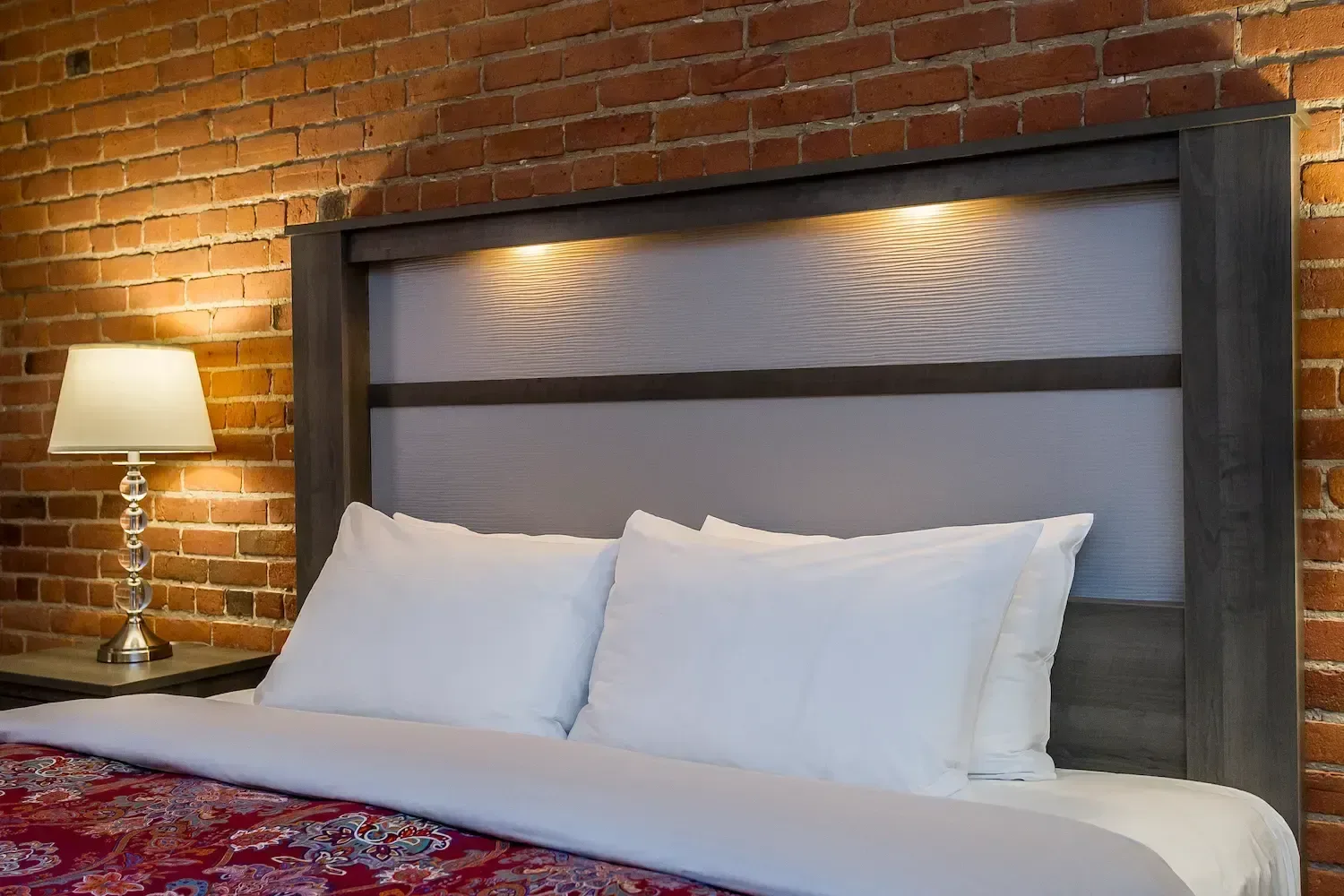 A hotel room with a bed and exposed brick wall.