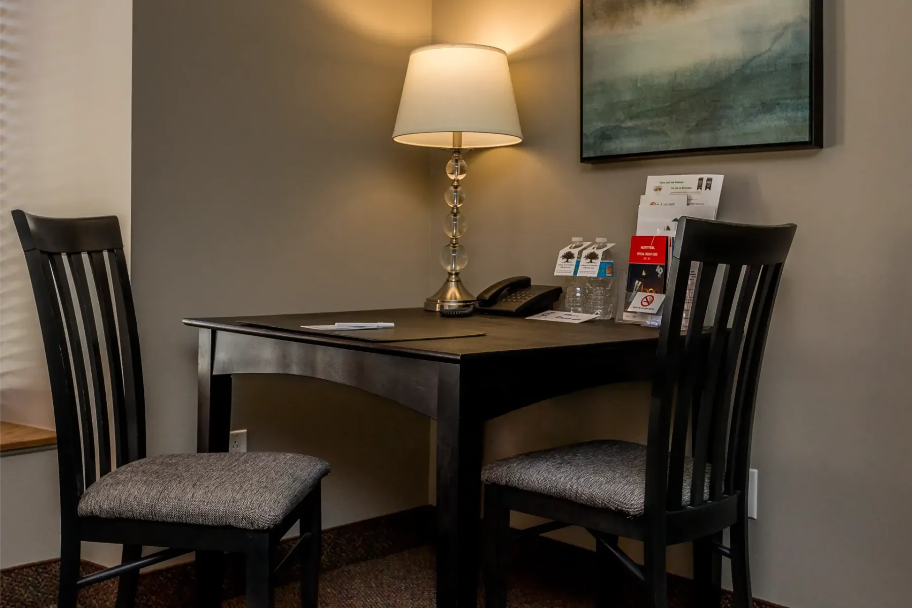 A desk with two chairs and a lamp in a hotel room.