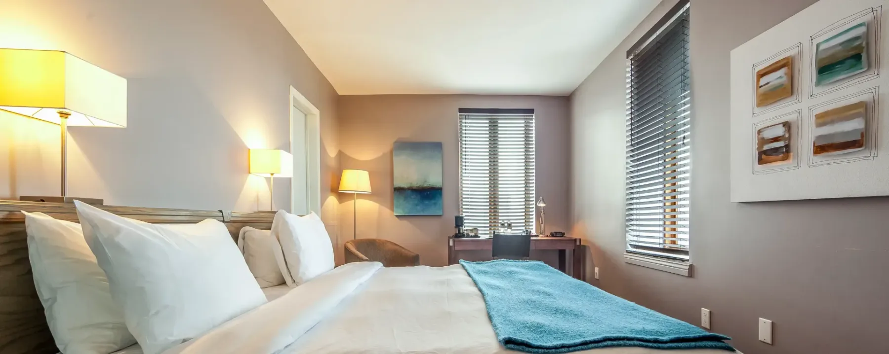 A room with a bed, lamps and window.