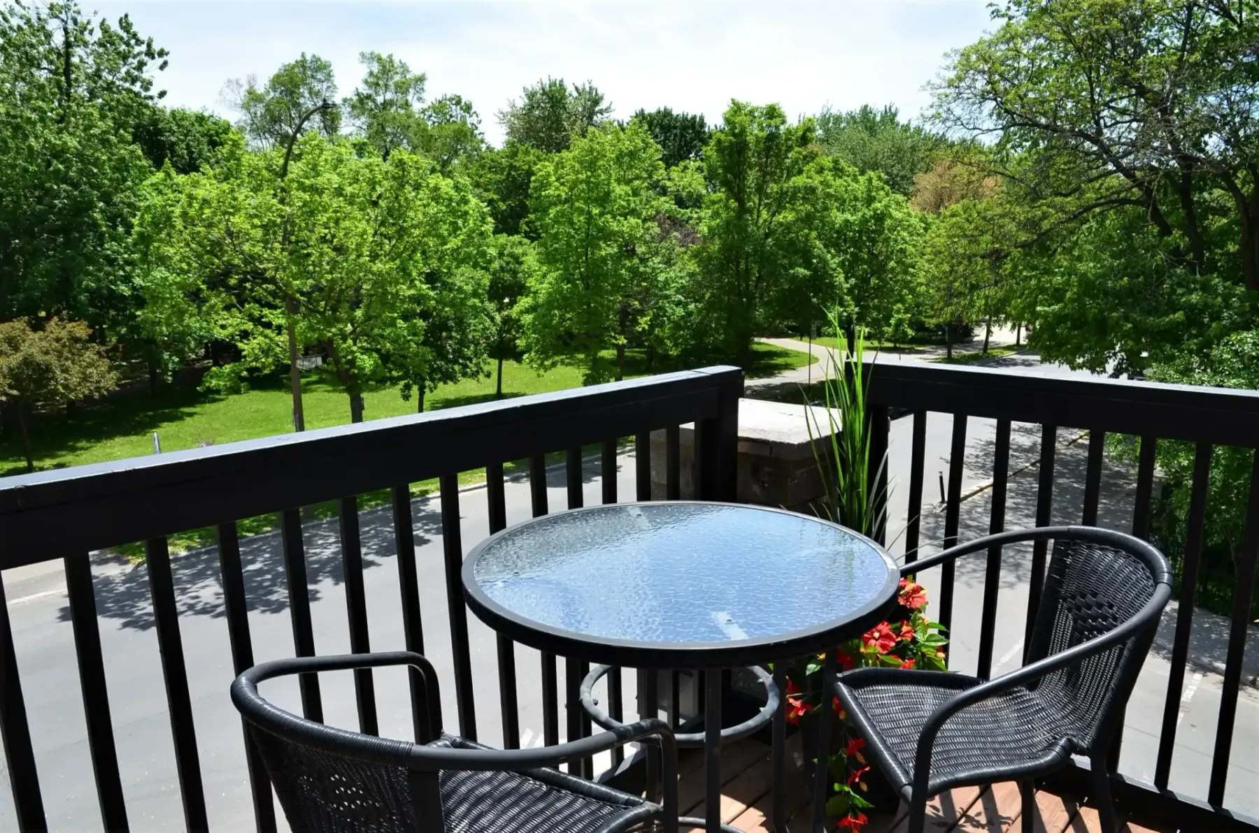 A balcony with a table and chairs overlooking a park.