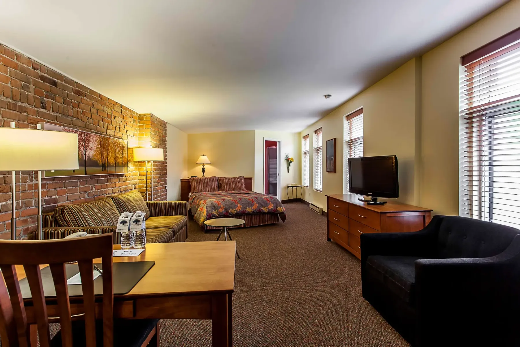 A hotel room with a large bed, sofa, table and chairs.