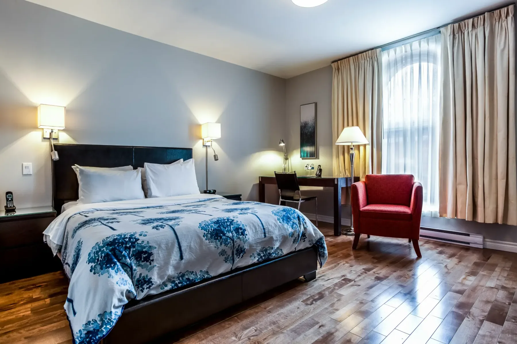 A hotel room with a bed and red chair.