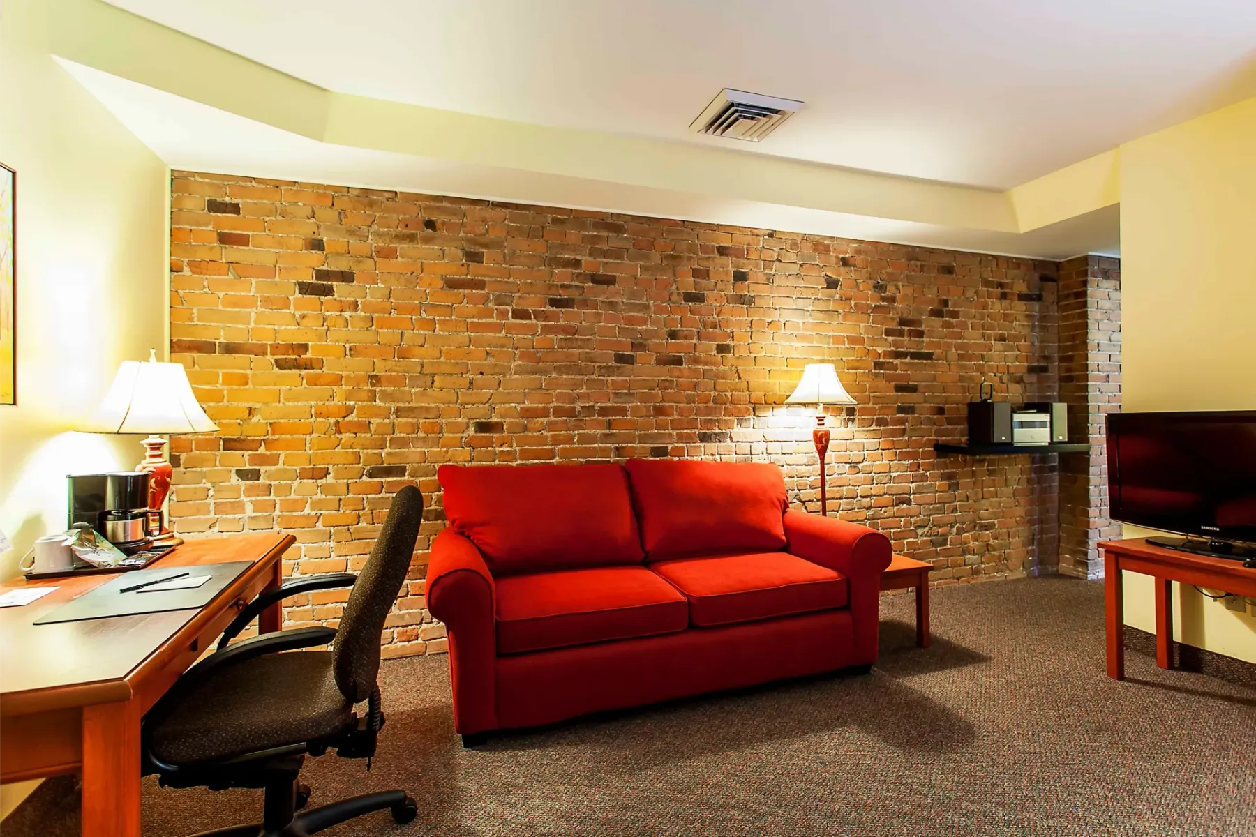 A lounge with a red sofa and exposed brick wall.