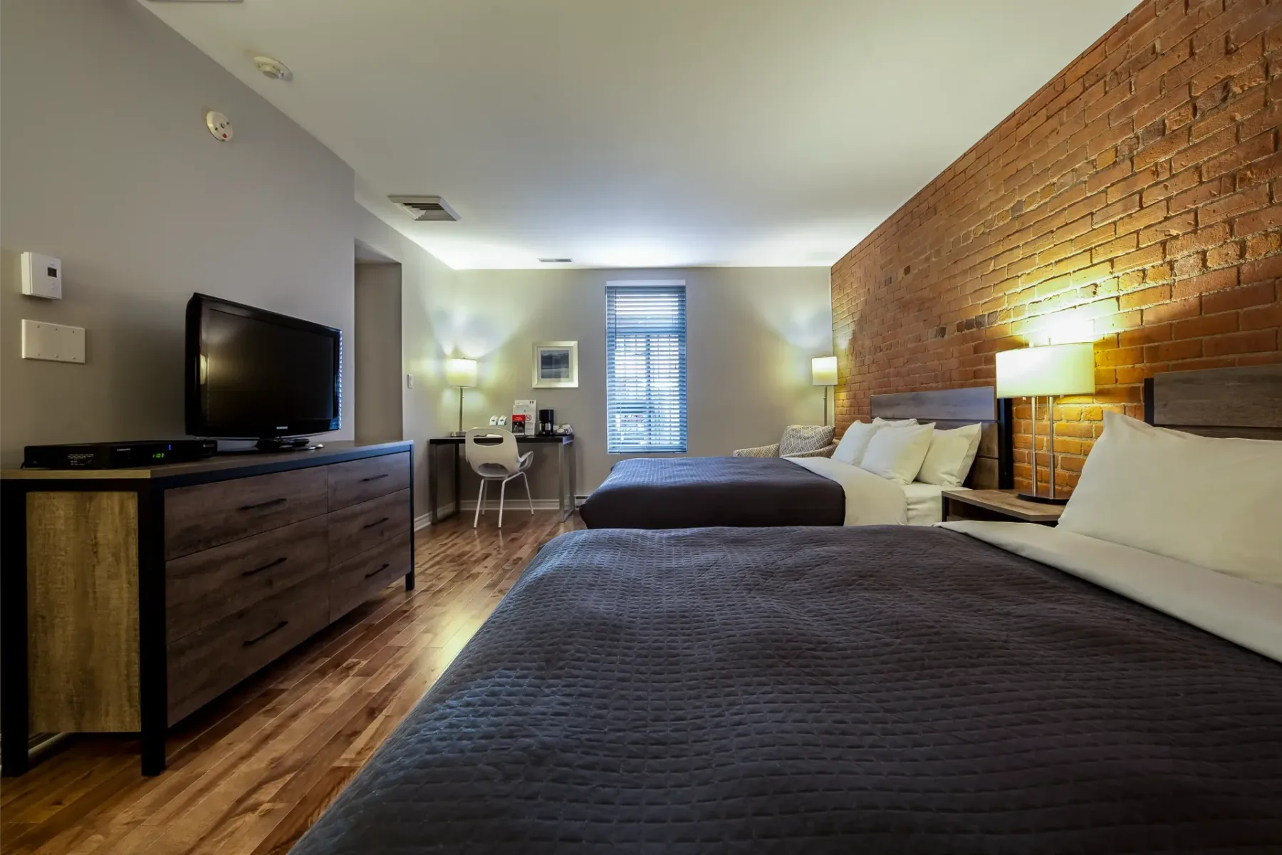 A hotel room with two beds and a television.
