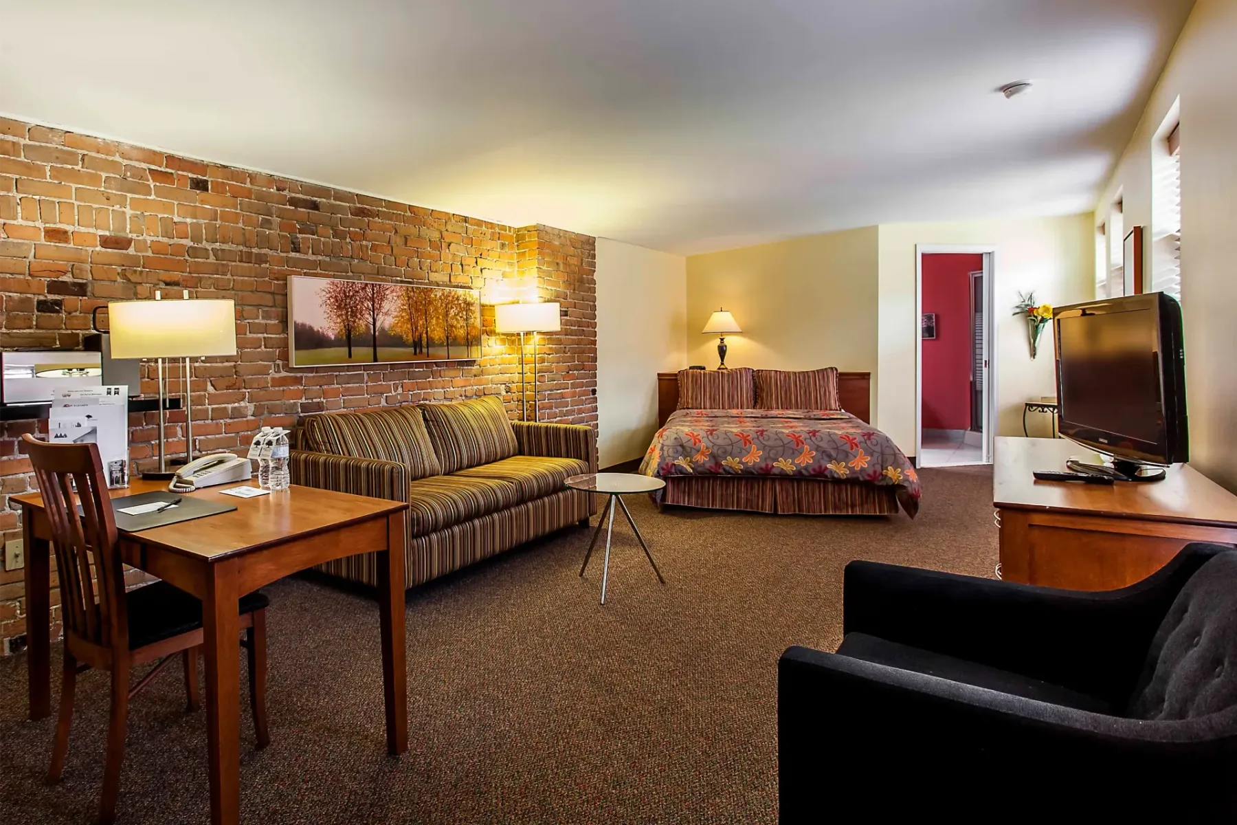 A hotel room with a large bed, sofa, table and chairs.