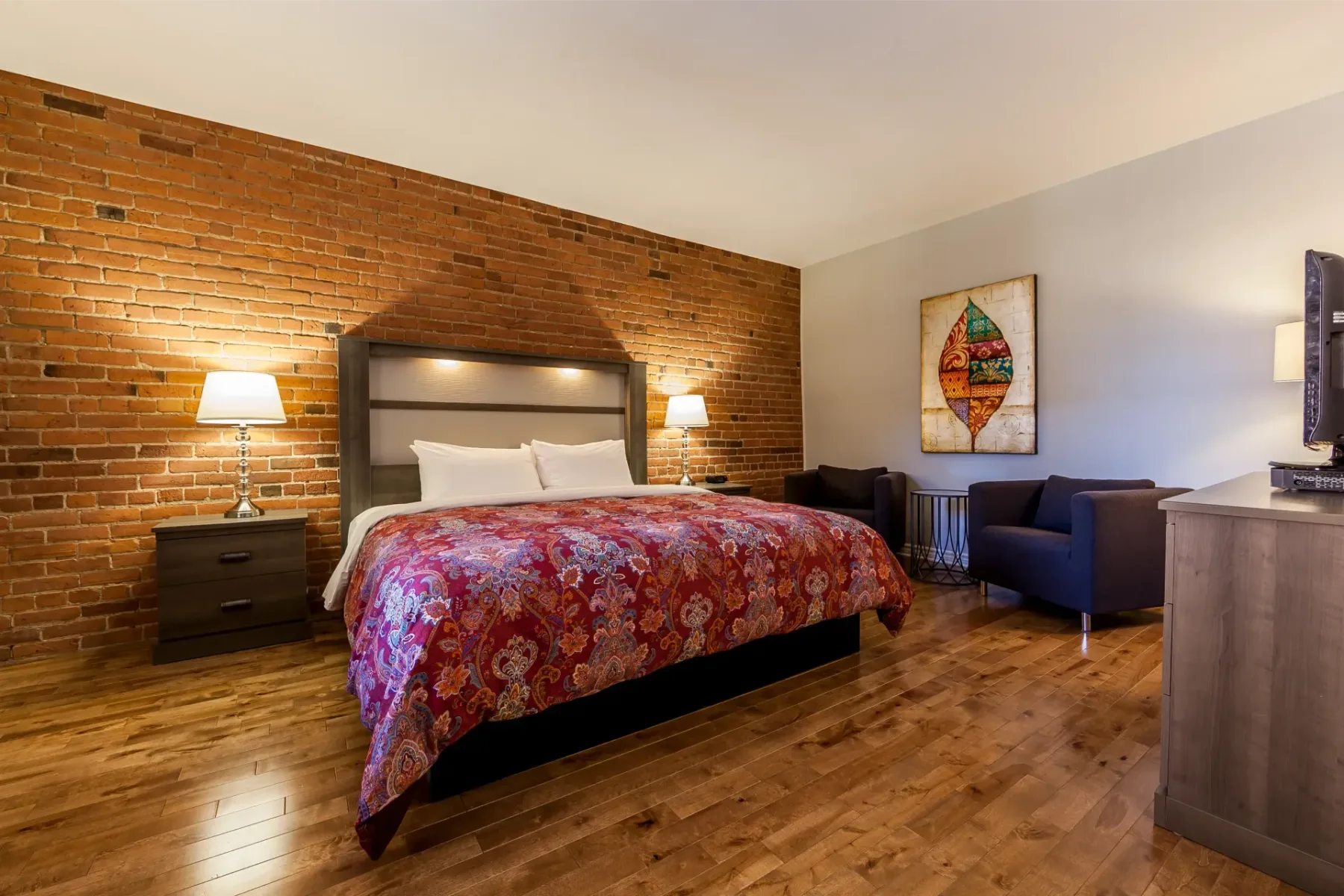 A hotel room with a large bed and exposed brick wall.