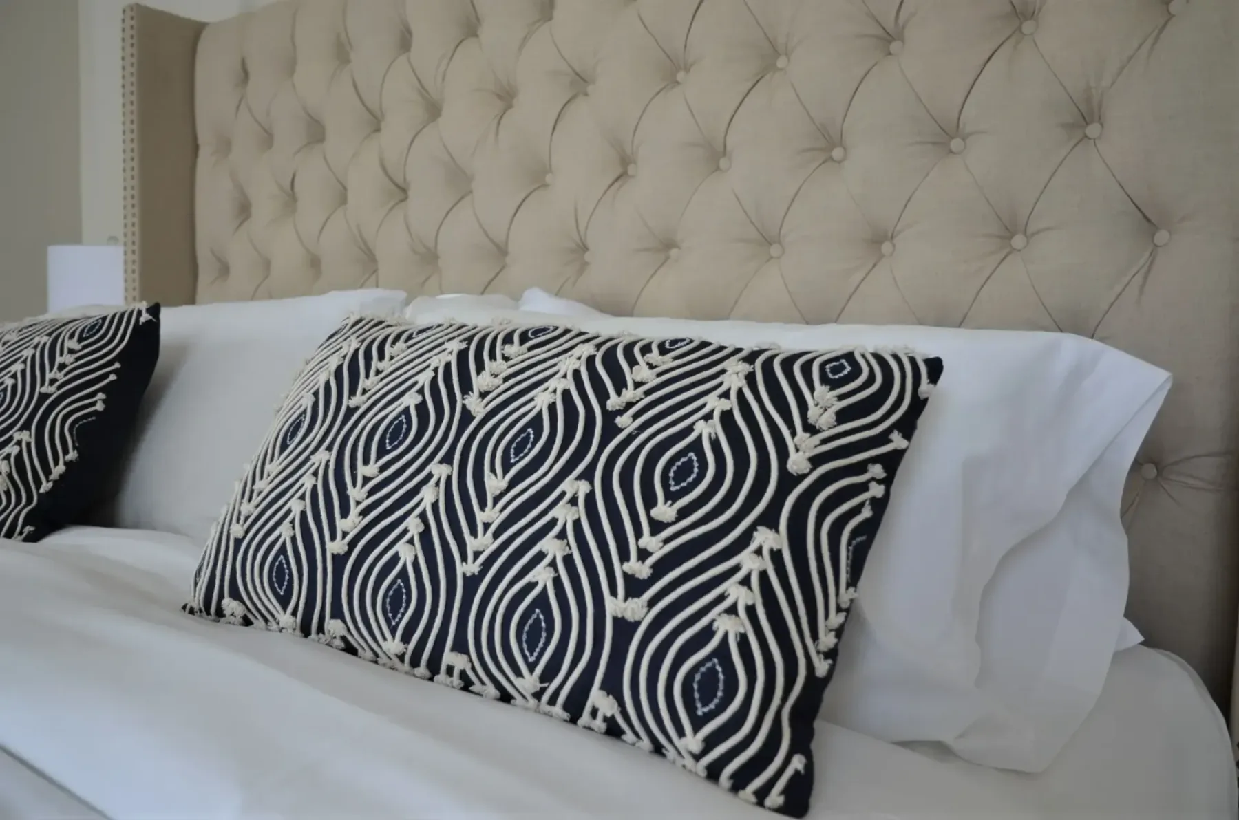 A hotel bed with black-and-white pillows.