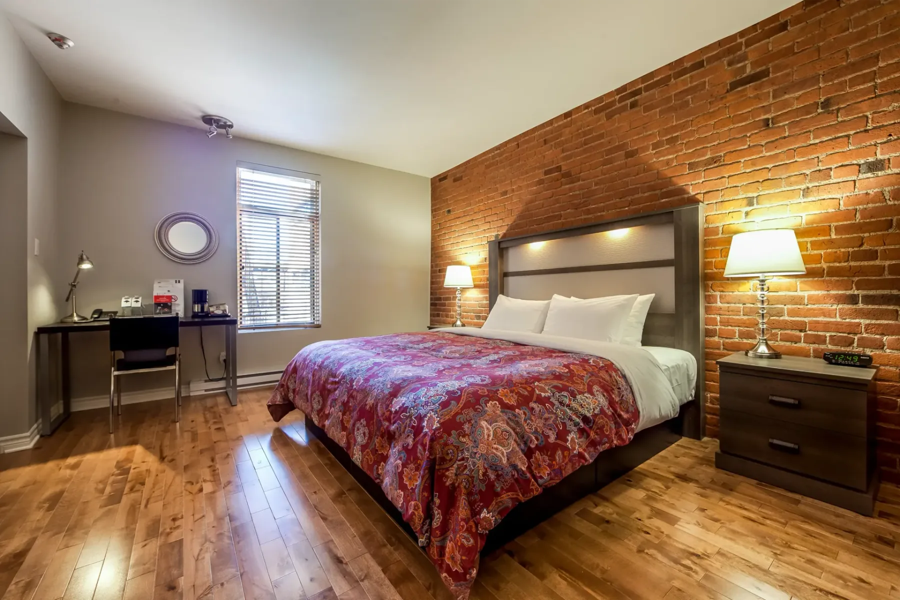 A hotel room with a large bed and an exposed brick wall.