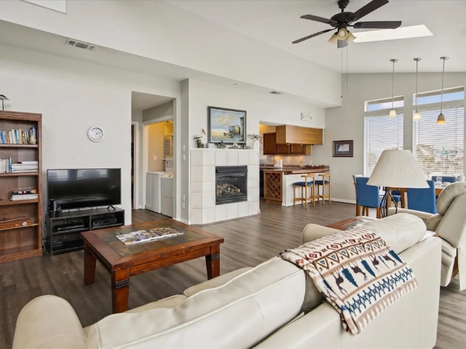 An open-plan living room with a fireplace, seating, and an adjoining kitchen.