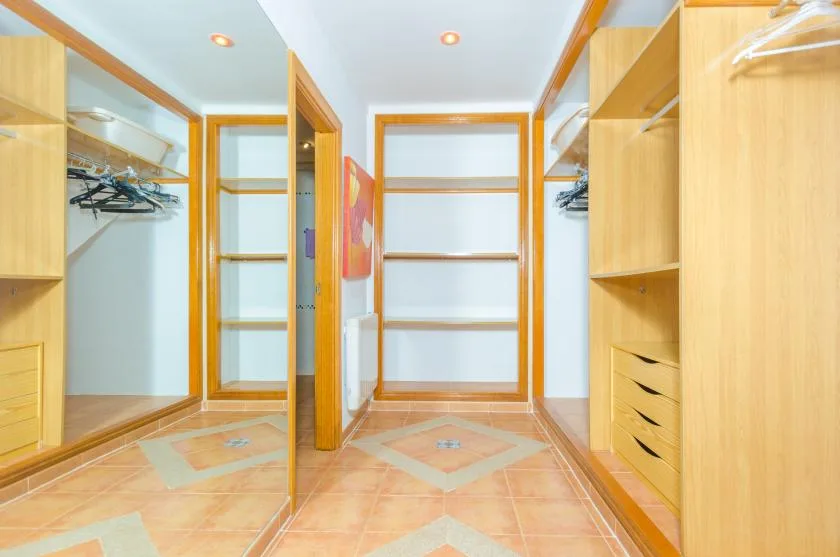 A walk-in closet with open shelving and hanging space along both sides.