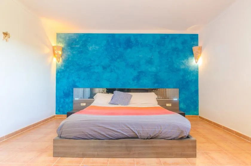 A bedroom with a bed centered against a blue accent wall.