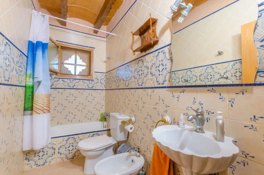 A tiled bathroom with a toilet, bidet, and pedestal sink.