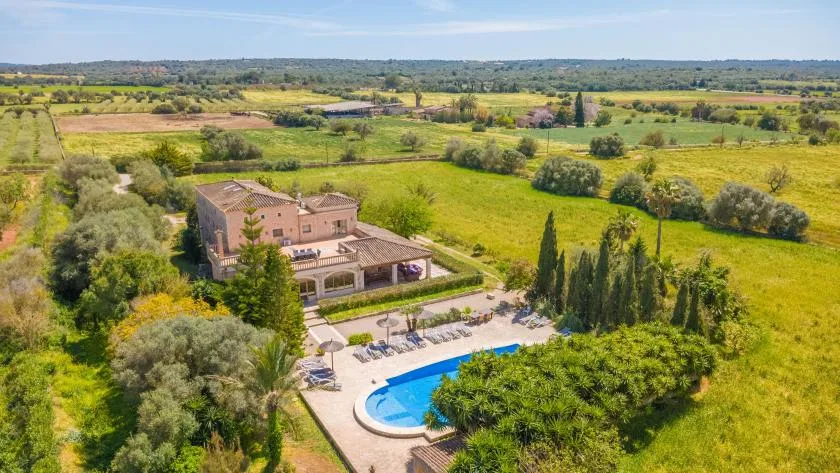 A countryside property with a swimming pool, gardens, and open fields.