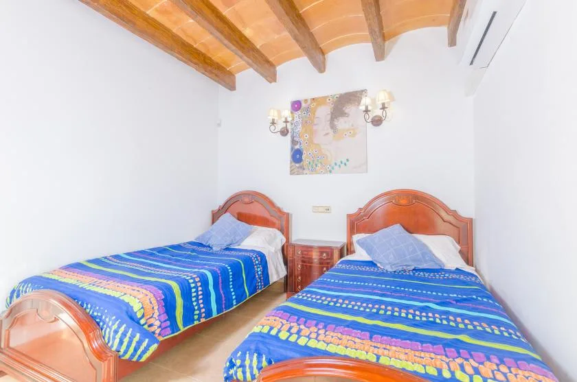 A bedroom with two beds covered in bright patterned bedding.