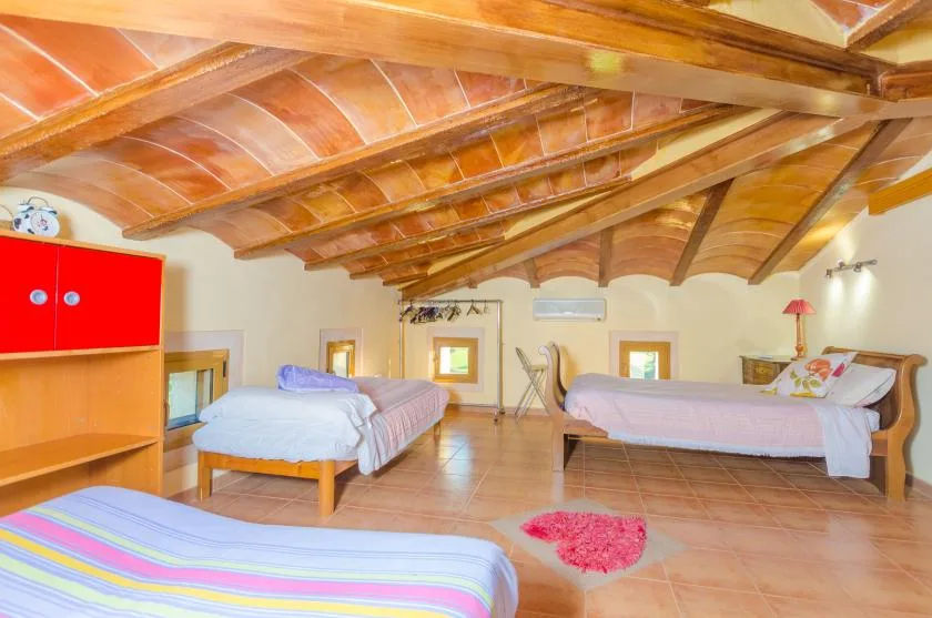A bedroom with several beds beneath a sloped wooden ceiling.