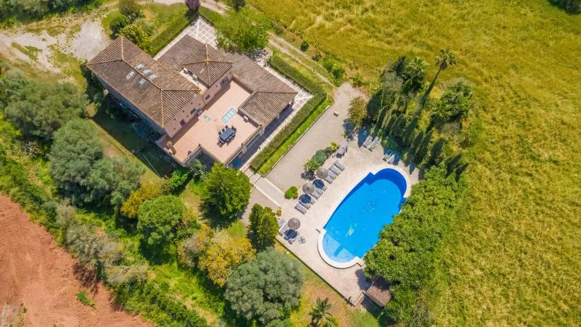 An aerial view shows a building beside a swimming pool and surrounding greenery.