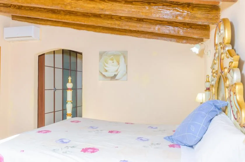 A bedroom with a patterned bedspread and blue pillows.
