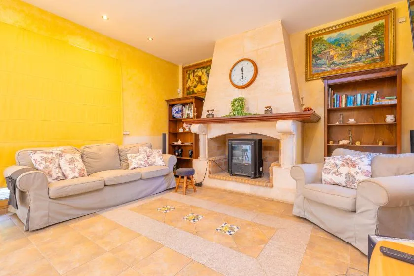 A living room with sofas arranged around a fireplace and bookshelves.