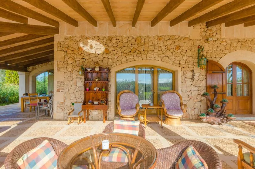 A stone-walled patio seating area with wooden ceiling beams and a garden view.