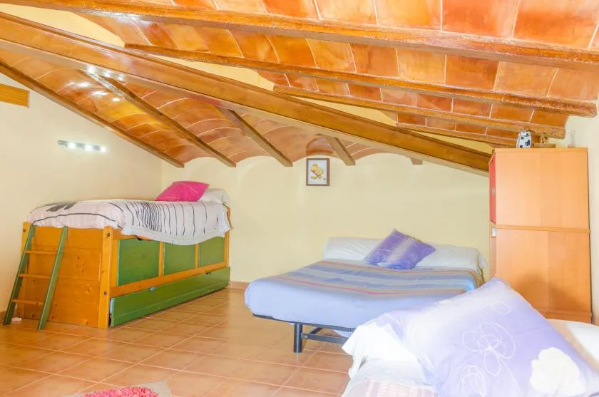 A bedroom with several beds beneath a sloped wooden ceiling.
